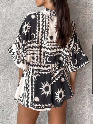 Black celestial print wrap romper with short sleeves and adjustable fit