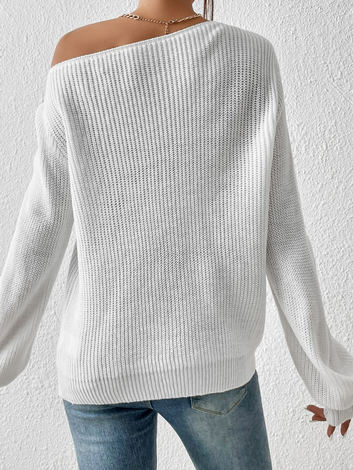 White ribbed knit off-shoulder top with balloon sleeves and a gold necklace.