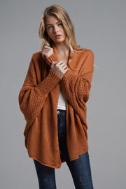 Terracotta acrylic cocoon knit sleeve cardigan with textured sleeves and open front.