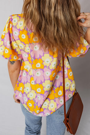 Puff sleeve blouse with a bold floral print in pink, yellow, and purple.