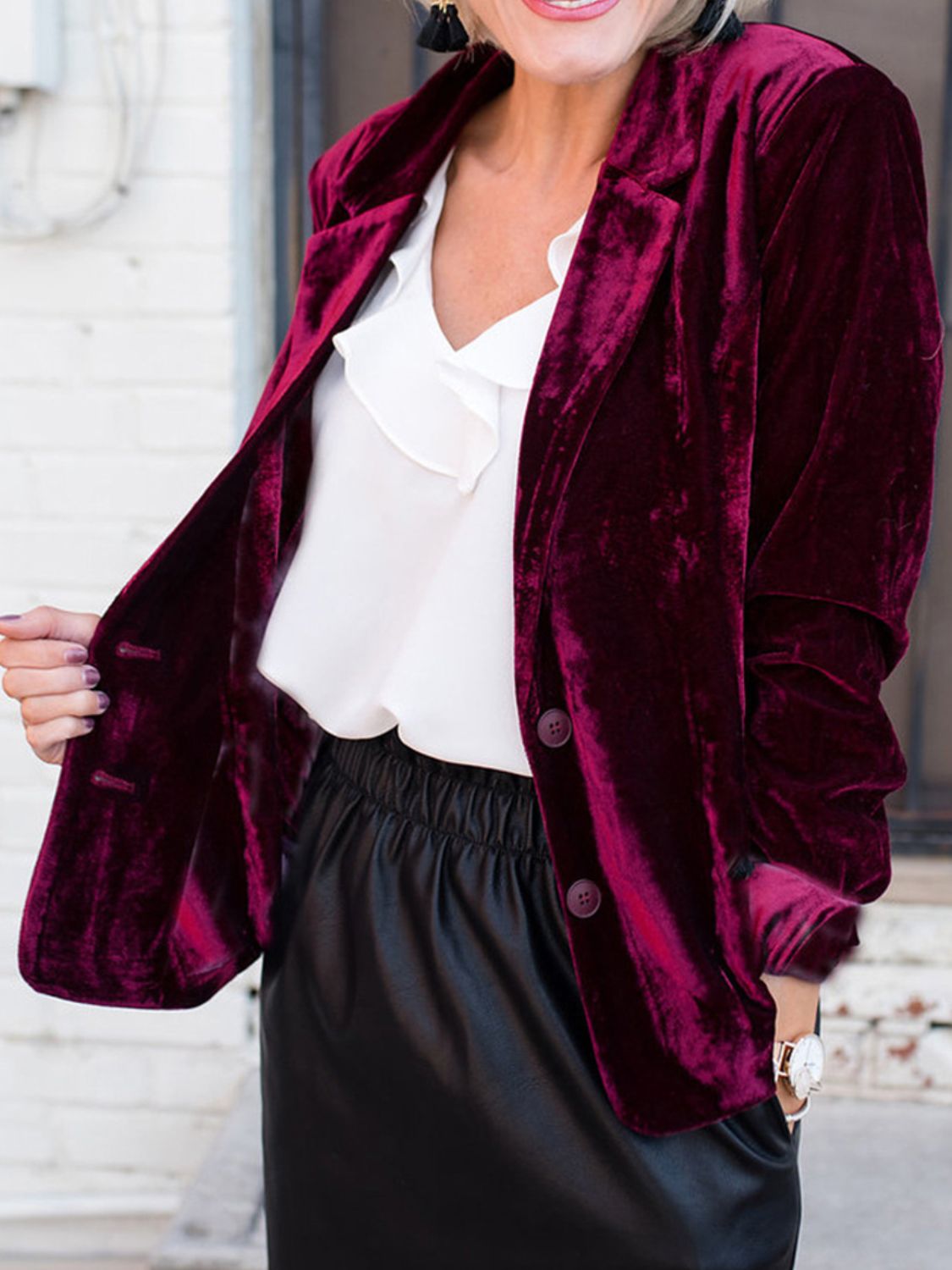 Burgundy velvet blazer with button closure and notched lapels, styled with a white ruffled blouse.