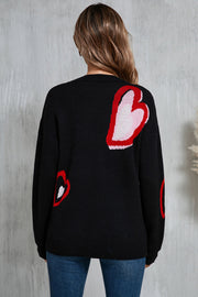 Black intarsia knit sweater with scattered red and white heart motifs.