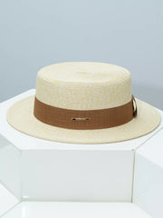 Elegant straw boater hat in beige with a brown ribbon band and gold detail.