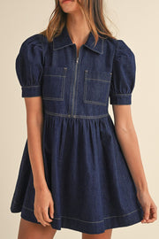Dark denim mini dress with puff sleeves, a zip front, and two chest pockets.