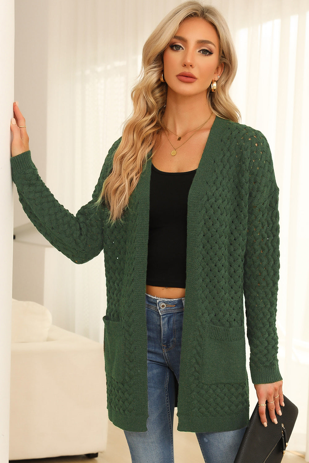 Dark green open-knit pocket cardigan with textured pattern and long sleeves.