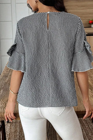 Black and white gingham polyester shirt with ruffled sleeves and bow tie detail.