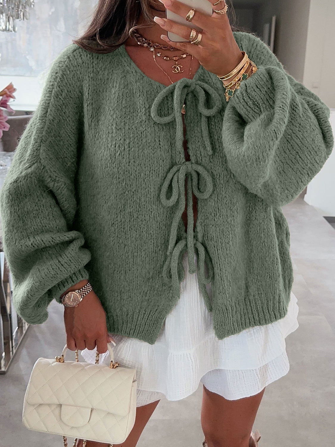 Moss green knit cardigan with balloon sleeves and tie front closure.