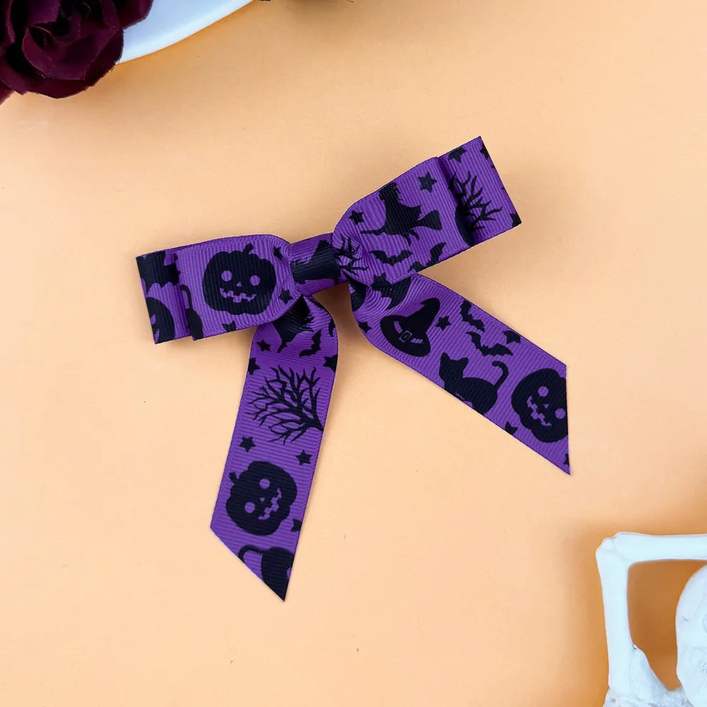 Violet Halloween print bow hair clip with pumpkins, witches, bats, and cats.