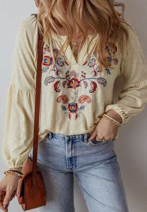Pastel yellow blouse with embroidered floral detail and poet sleeves.