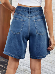 Pleated denim bermuda shorts in medium wash with button closure and back pockets.