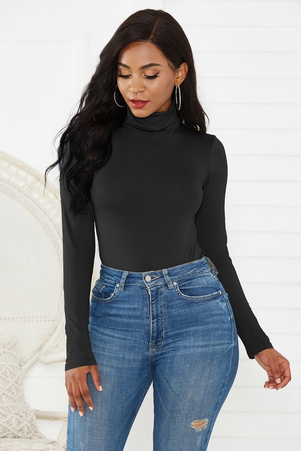 Black turtleneck thong bodysuit with long sleeves, styled with high-waisted jeans.