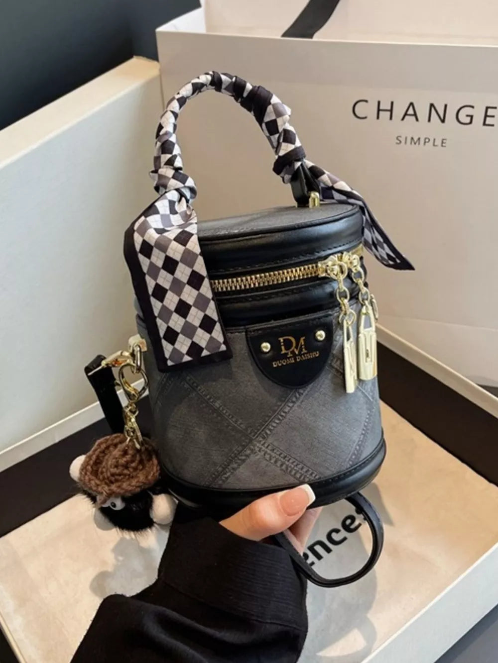 Quilted mini bucket bag in black with checkered scarf detail and charm.