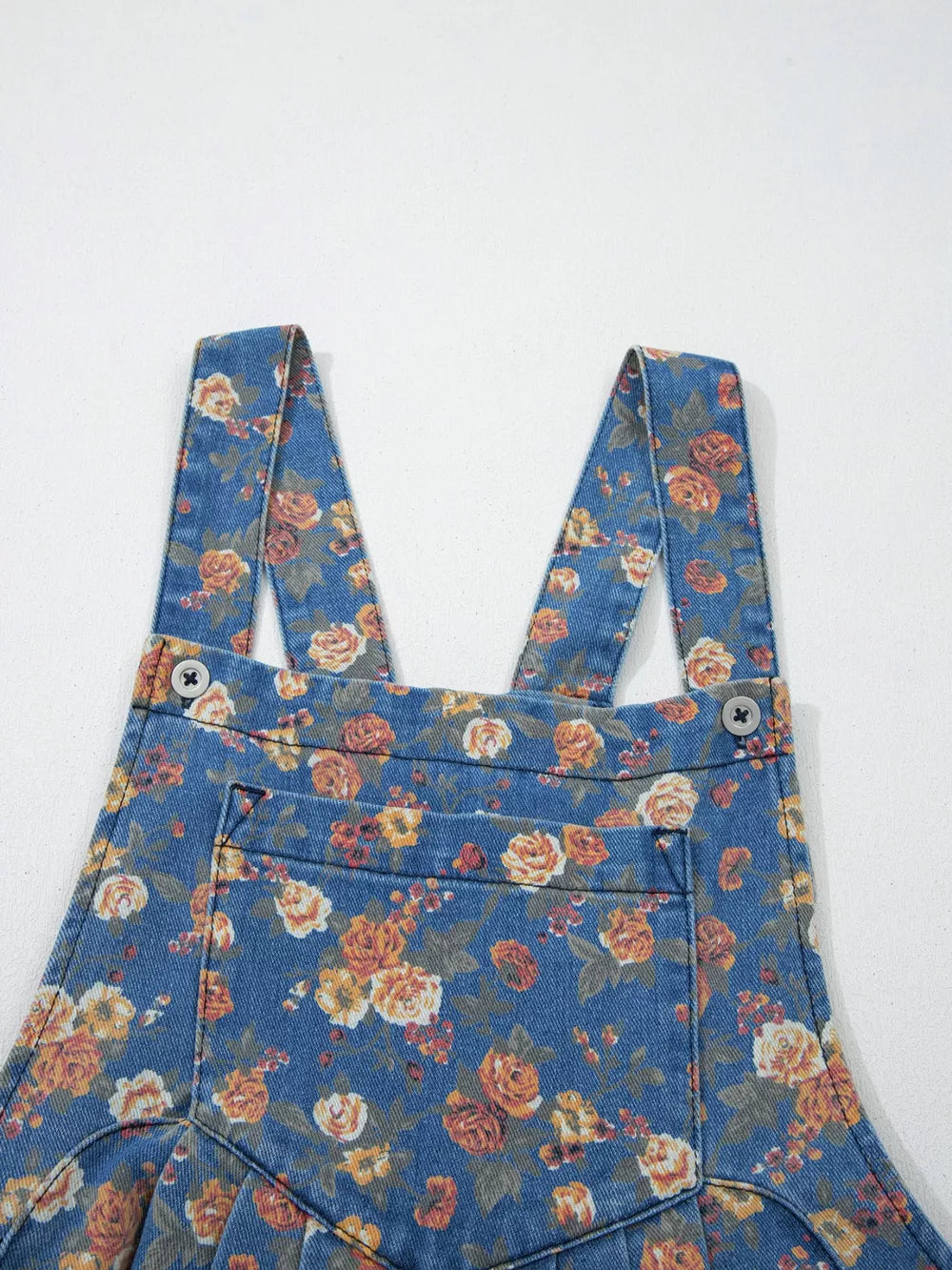 Floral denim overalls with adjustable straps and button details.