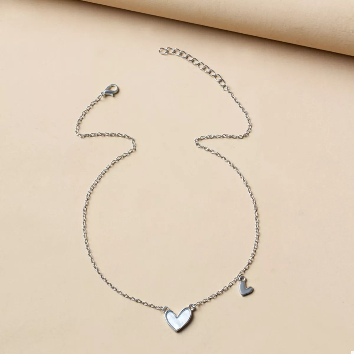 Silver chain necklace with a white heart pendant and a small heart charm.