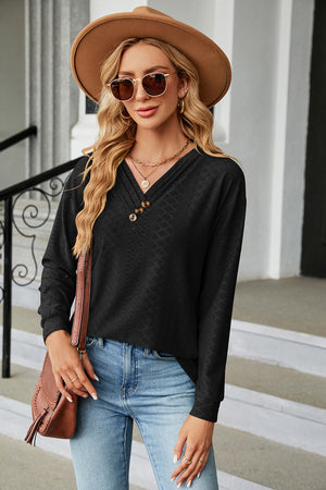 Textured black henley v-neck top with button detail and long sleeves.