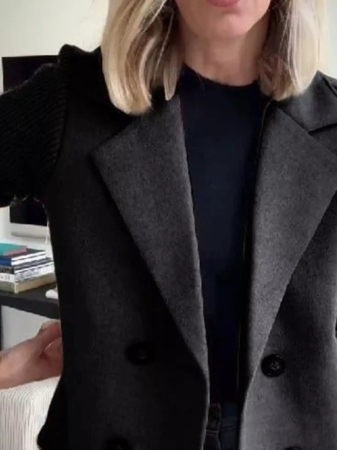 Double-breasted gray trench coat with black knit sleeves and dark buttons.
