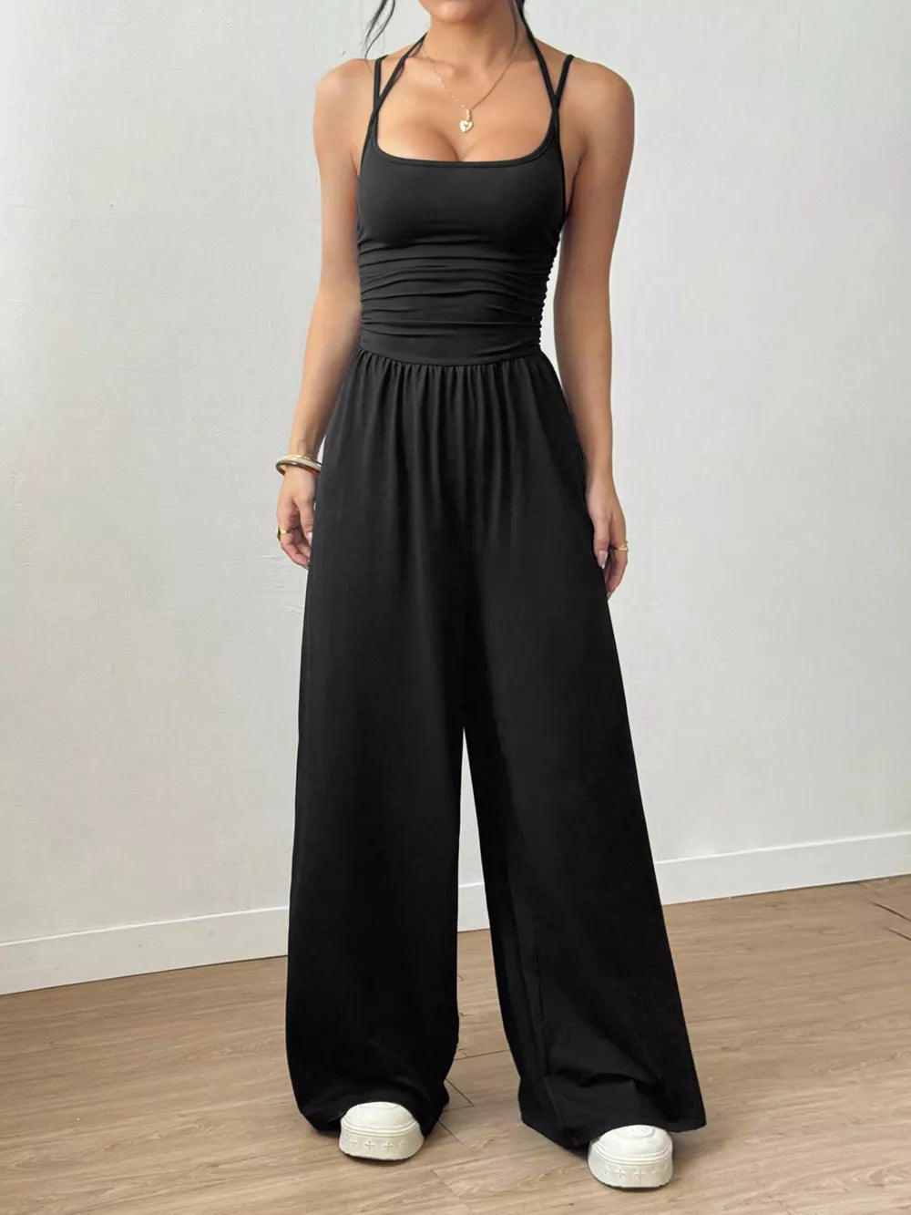 Black ruched wide-leg jumpsuit with spaghetti straps and a square neckline.