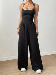 Black ruched wide-leg jumpsuit with spaghetti straps and a square neckline.