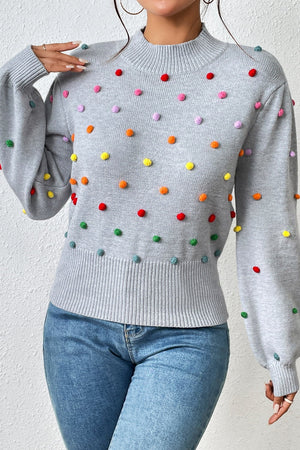 Light gray blouson sweater with colorful pom-pom embellishments and balloon sleeves.
