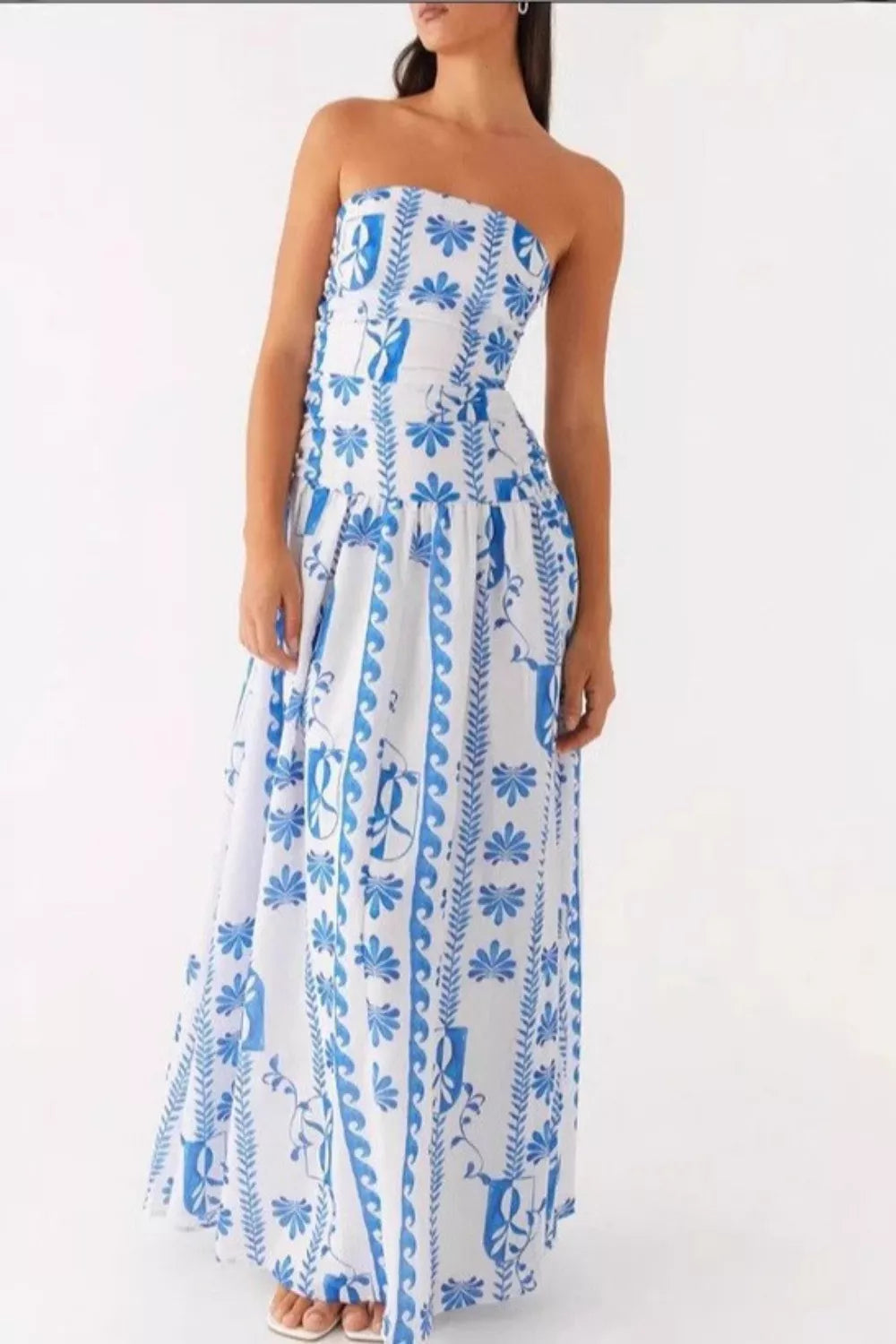 Strapless maxi dress in white with blue floral print and flowing skirt.