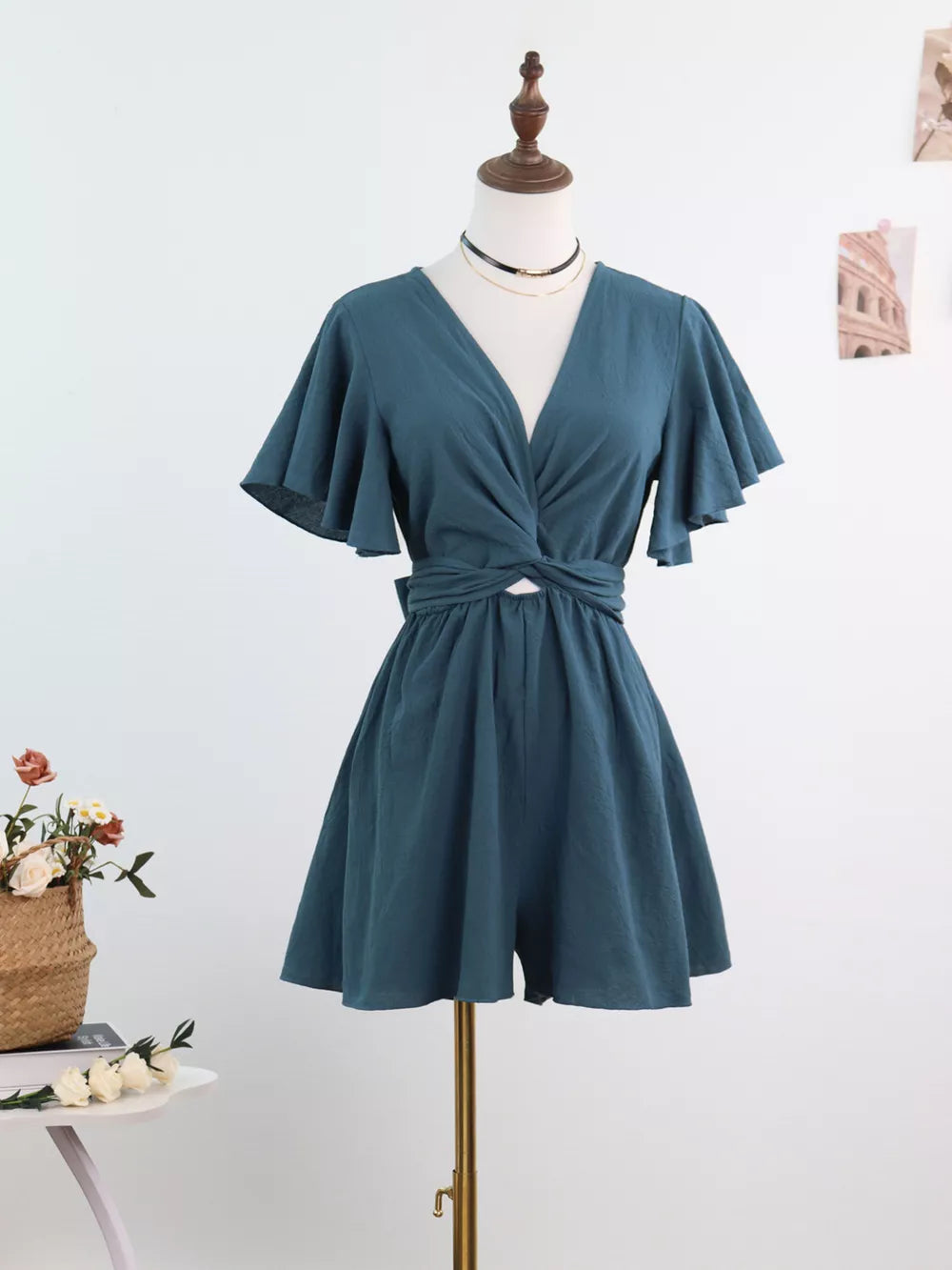 Haze Blue cotton romper with flutter sleeves, deep V-neck, and tie waist.