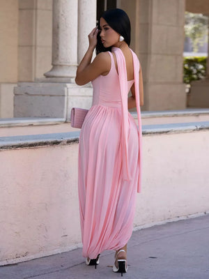 Blush pink maxi dress with scoop neck, draped skirt, and flowing back sash.