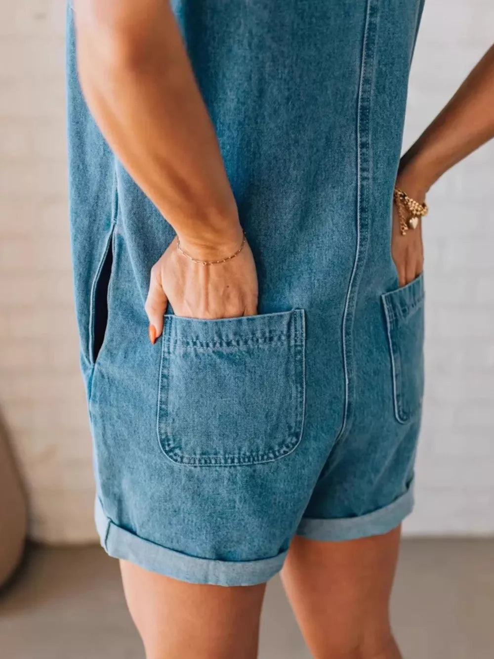 Denim romper with cuffed shorts, back pockets, and zipper closure.