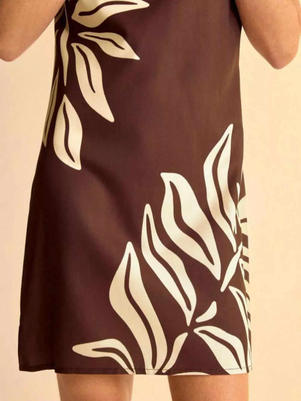 Tropical leaf print mini dress in brown with cream botanical pattern, A-line cut.