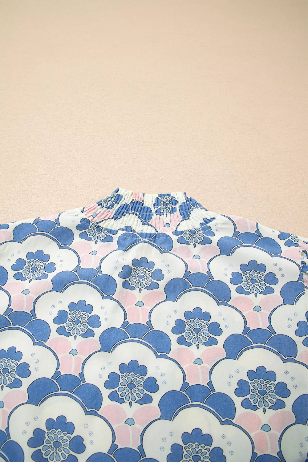 Playful floral print polyester blouse with a smocked mock neck and puff sleeves.