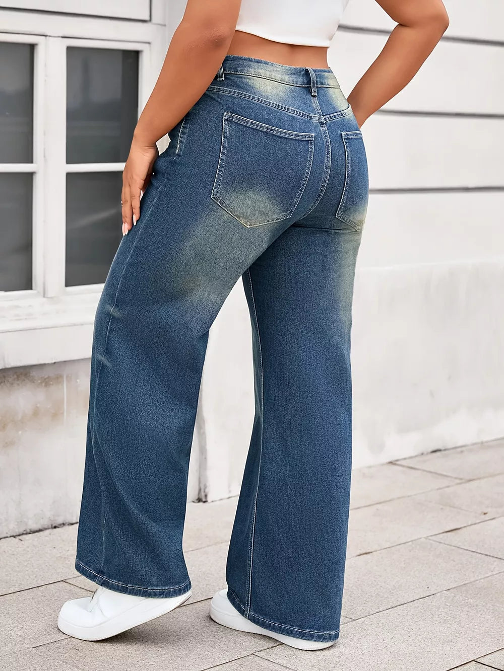 Plus size wide leg blue denim jeans with vintage wash and flared hem.