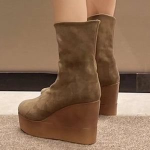 Brown suede wedge boots with a platform sole and a smooth leather wedge.