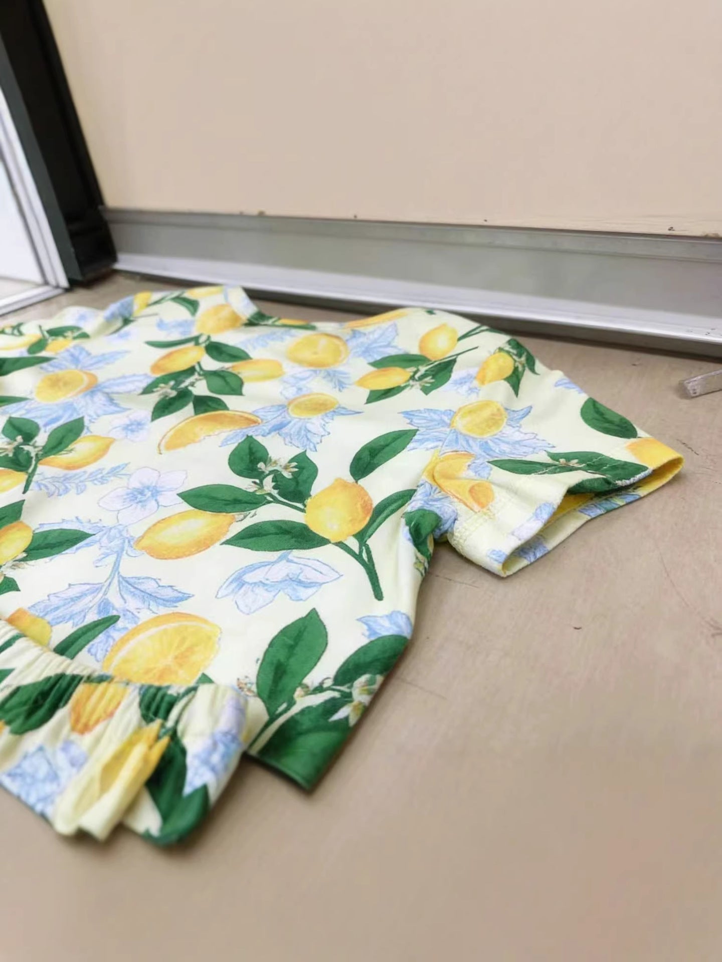 Toddler outfit set with lemon print, short sleeves, and ruffled hem.