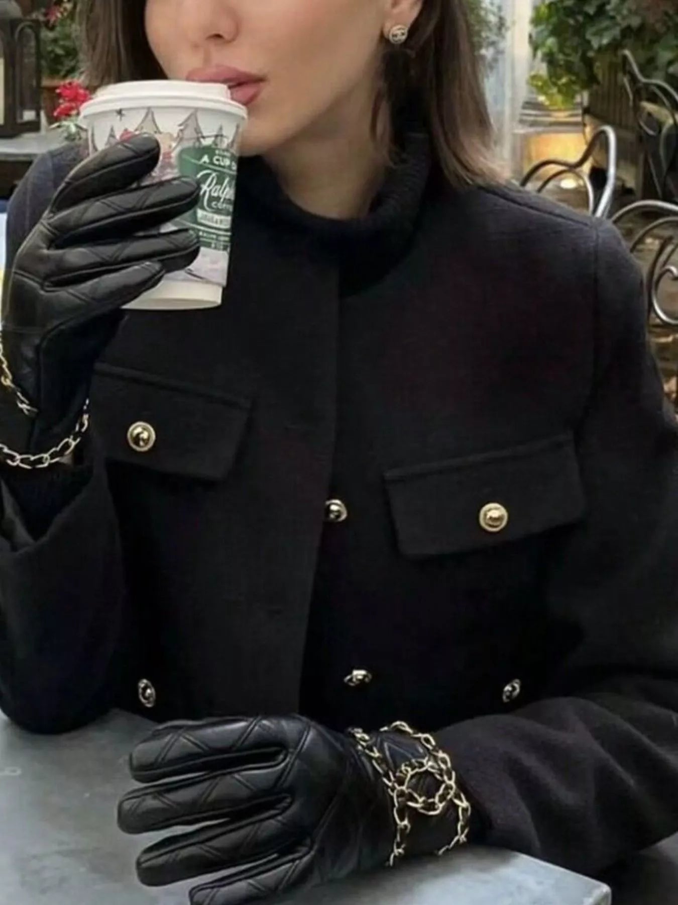 Black cropped tweed jacket with gold button details and chain accents on black leather gloves.