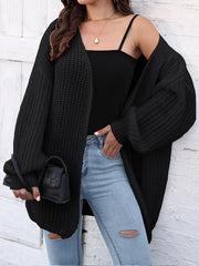 Black open knit cardigan with balloon sleeves and ribbed cuffs, styled with a tank top and ripped jeans.