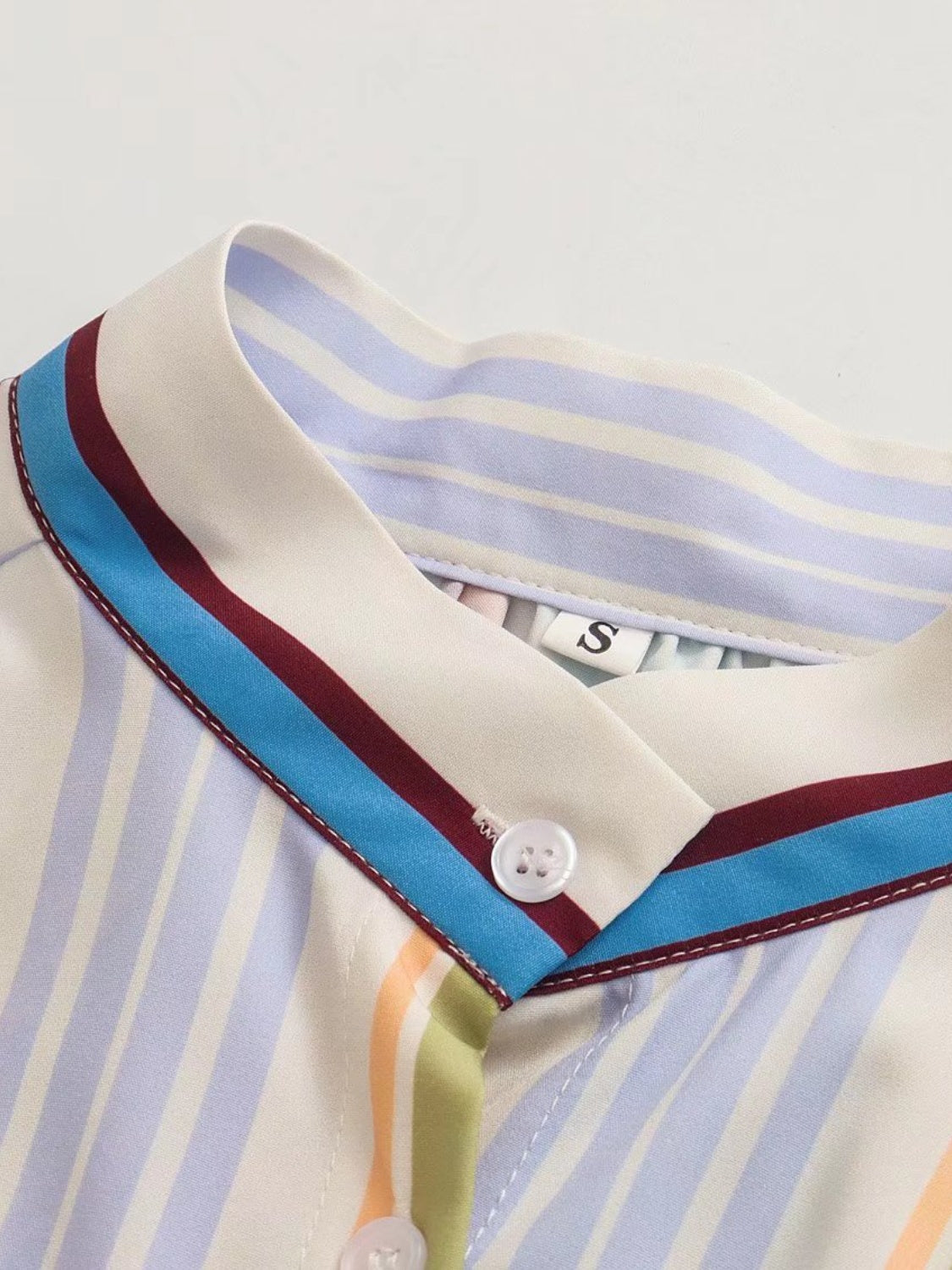 Prismatic stripe band collar blouse with button detail and multicolor stripes.