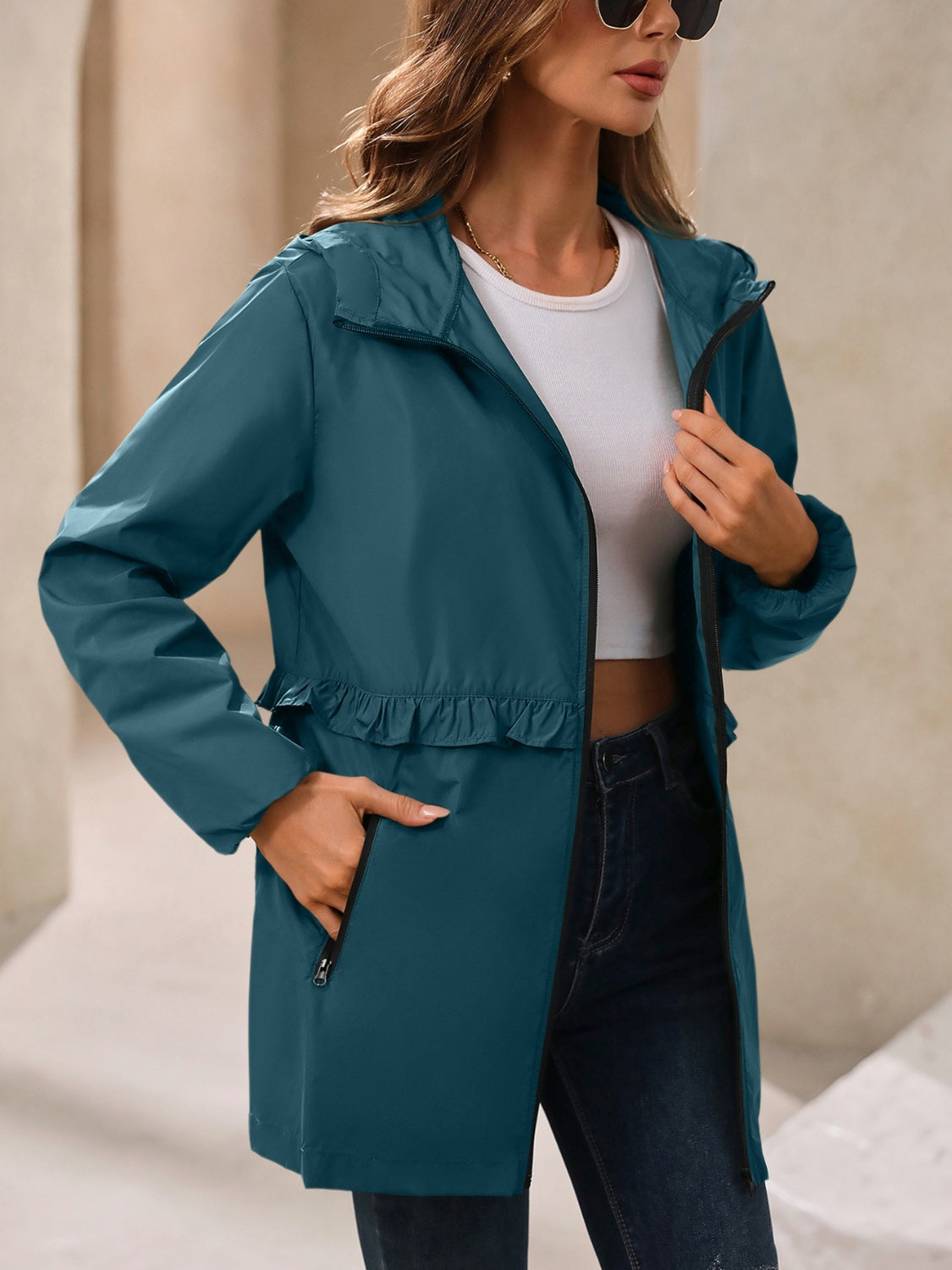 French blue hooded windbreaker jacket with ruffled waistline and zippered pockets.