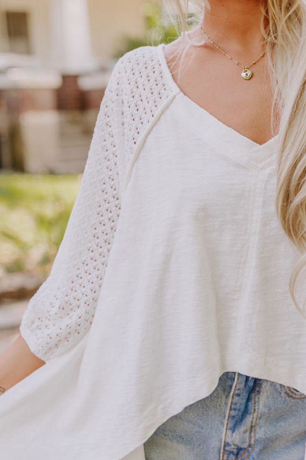 White blouse with V-neck and lace inset dolman sleeves.