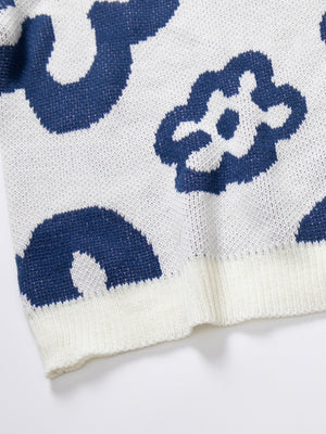White acrylic knit crewneck sweater with a blue abstract floral pattern and ribbed trim.