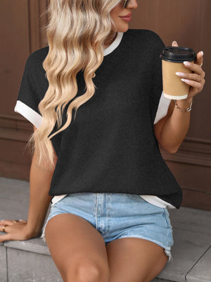 Black textured knit short-sleeve t-shirt with white trim, worn by a woman holding a coffee cup.