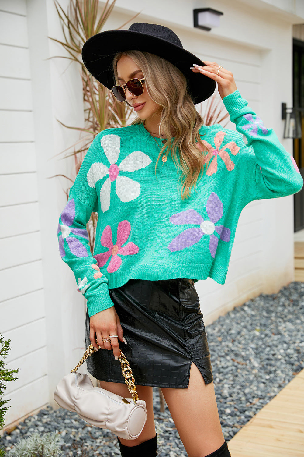 Teal acrylic sweater with drop shoulders and a colorful daisy motif pattern.