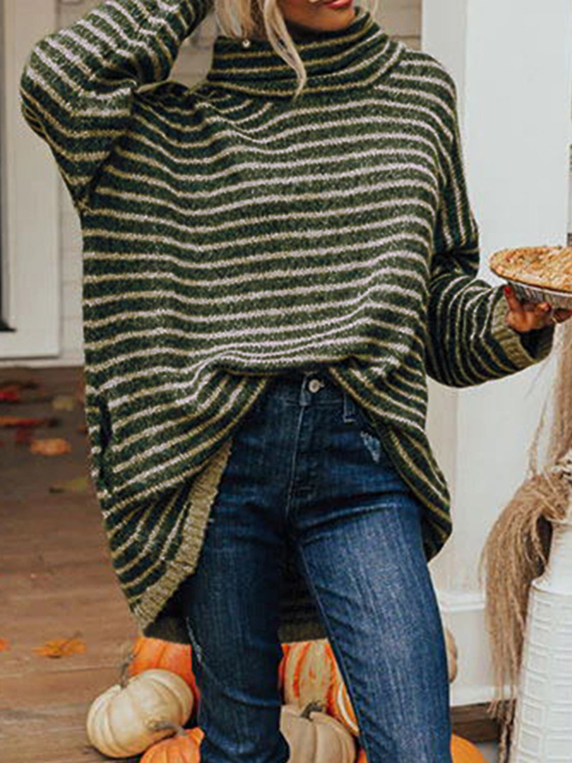 Dark green and gold striped oversized turtleneck sweater with slouch pockets, worn with jeans.