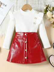 Red faux leather a-line skirt with decorative buttons paired with a white ribbed long-sleeve top with ruffled shoulders.