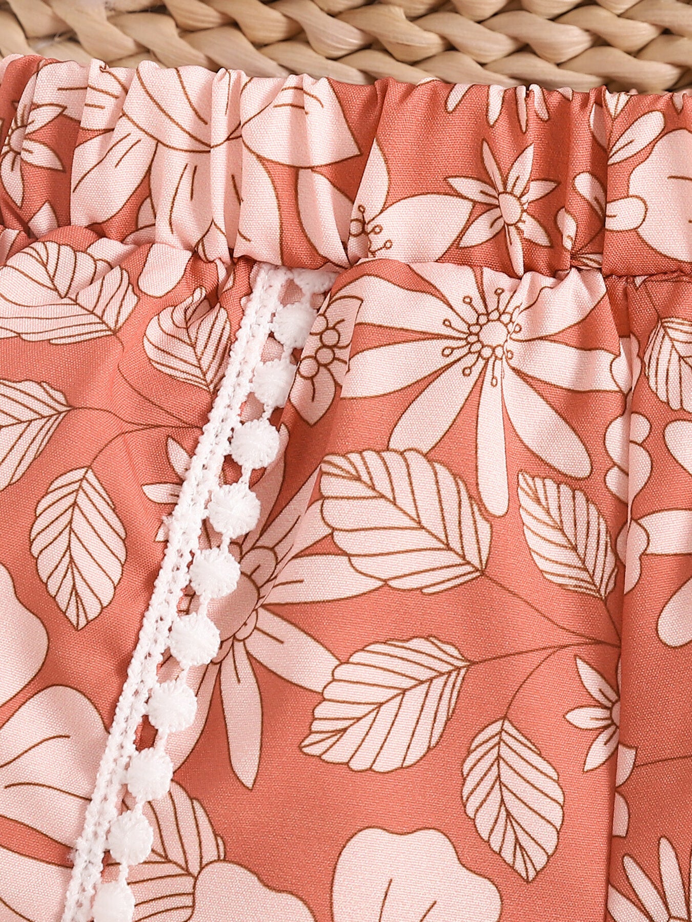 Light brown floral print baby shorts with elasticated waist and white pom-pom trim.