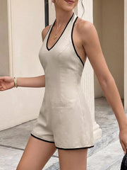 Beige halter neck romper with contrast trim and pocket detail.