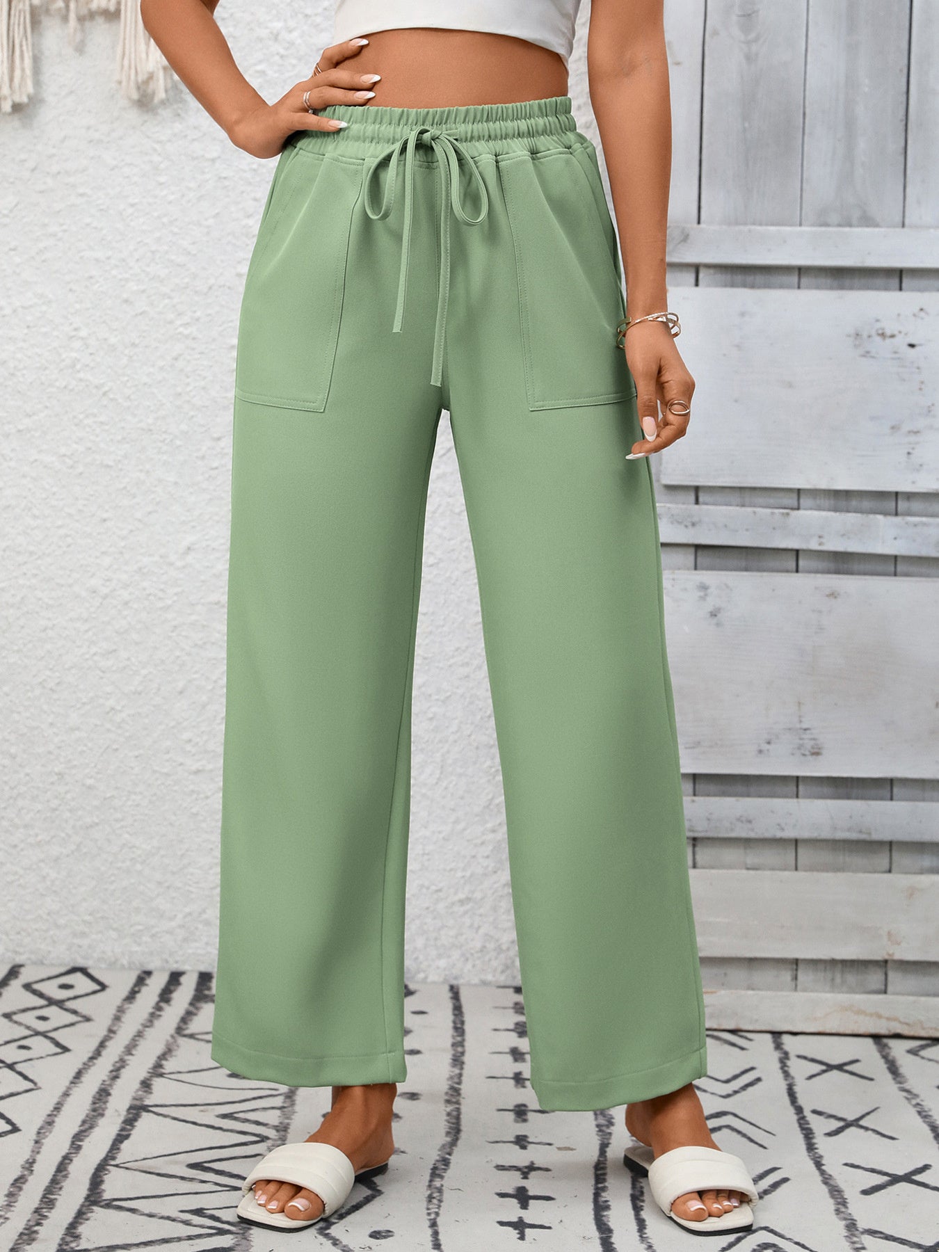 Green drawstring wide-leg pants with pockets, styled casually.