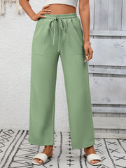 Green drawstring wide-leg pants with pockets, styled casually.