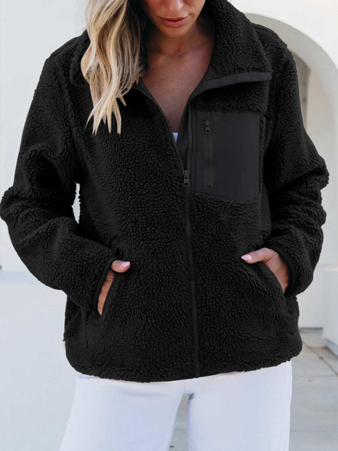 Black sherpa zip-up jacket with patch chest pocket and side pockets.