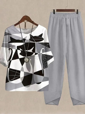 Gray pants and a white half sleeve top with a black and gray abstract cat print.