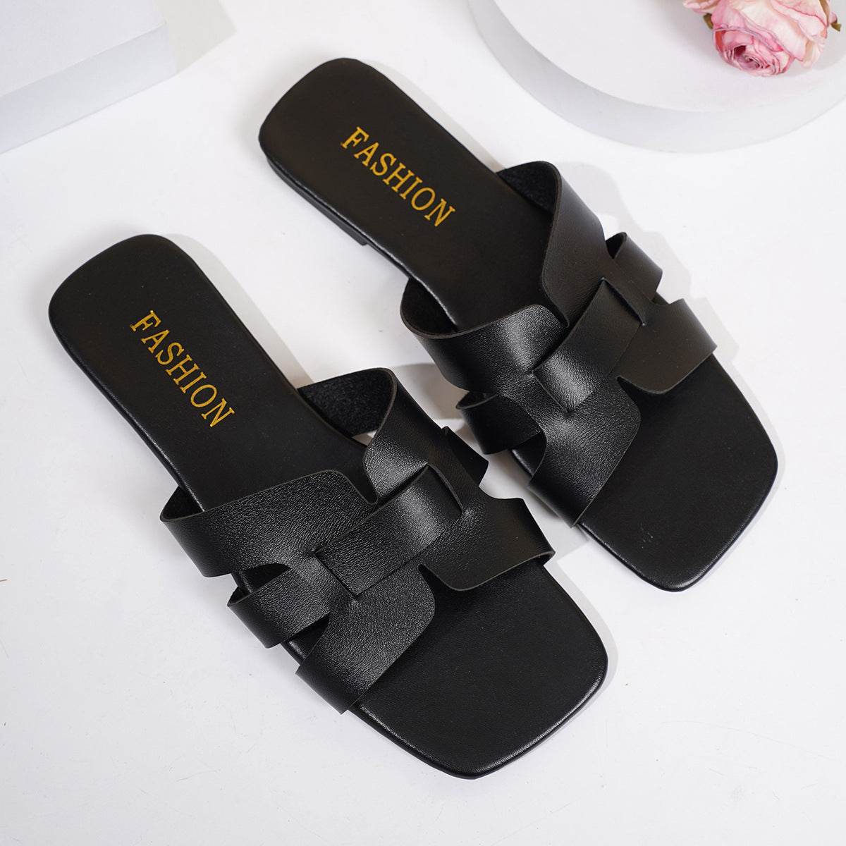 Chic woven strap slide sandals in black with square toe and gold "FASHION" detail.