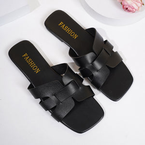 Chic woven strap slide sandals in black with square toe and gold "FASHION" detail.